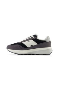 Sportlicher Schuh mit grauem Wildleder und schwarzem Mesh-Obermaterial, ausgestattet mit einem weißen Logo, weißen Schnürsenkeln und einer massiven weißen Sohle. Schwarzes Profildesign.