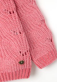 Rosa gestrickter Pullover mit strukturiertem Material, offenen Maschen-Details und einem kleinen, herzförmigen goldenen Akzent an einem Ärmel.