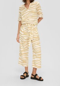 Completo a due pezzi composto da una maglietta a maniche corte con scollatura a V e pantaloni a gamba larga con una fantasia a righe zebra gialle e bianche. Tessuto testurizzato.