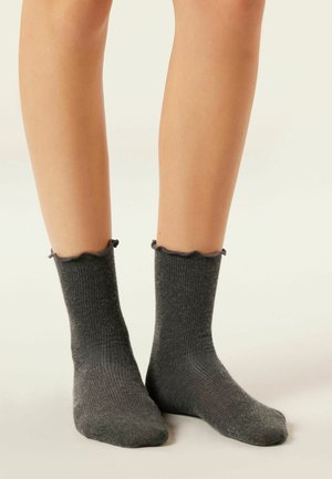 Chaussettes de cheville côtelées gris foncé avec un bord festonné, fabriquées dans un matériau doux, présentant un motif texturé et un ajustement confortable autour de la cheville.