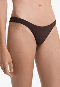 Rjavi bikini spodnji del s tankimi bočnimi trakovi. Gladka tekstura in zasnova z minimalnim pokrivanjem, primerna za kopalke.