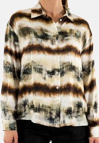 Camicia abbottonata in tessuto leggero con un motivo ondulato in tonalità beige, marrone e verde; colletto appuntito e maniche lunghe.