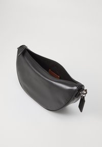 Borsa a mano in pelle nera con una texture liscia, forma a mezzaluna, chiusura a zip e un piccolo cartellino. Interno visibile con un accento arancione.