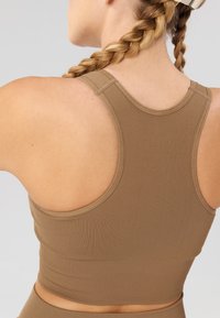 Top court en maille côtelée marron avec un dos en forme de scoop et de larges bretelles, fabriqué à partir d'un matériau élastique.