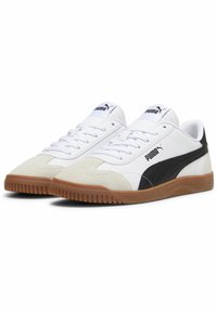Białe sneakersy z czarnymi akcentami, zamszowym przodem i piętą, gumową podeszwą oraz sznurowaniem. Logo PUMA na języku i boku.