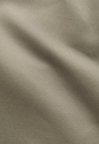 Beige fabric with fine diagonal twill weave and smooth, slightly wrinkled texture under soft lighting.