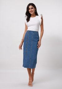 Denimkjol med knäppning fram, rak skärning och sidofickor. Bärs med en vit ribbad topp med volangärmar.