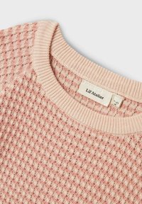 Maglione rosa chiaro con texture, motivo a rombi e collo a coste. L'etichetta riporta "Lil'Atelier." Il materiale sembra morbido e lavorato a maglia.