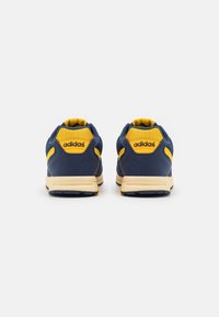 Blå och gula Adidas-sneakers med en texturerad vävoverdel, vadderad krage och gummisula. Har en framträdande logotyp på hälen.