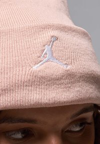 Roze gebreide beanie van zachte stof met een witte geborduurde Jumpman-logo aan de voorkant. De textuur is geribbeld en aansluitend.