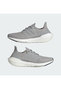 Scarpe sportive grigio chiaro con tomaia in maglia, sovrapposizioni testurizzate e suole bianche ammortizzate. Le caratteristiche includono un design a profilo basso e una vestibilità flessibile.