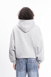 Grå hettegenser med romslig design og stor hette. Har dråpe-skulder og en myk tekstur. Bæres med blå denimjeans.