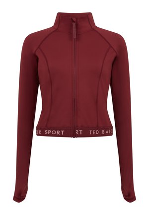 Bordó színű sportdzseki magas gallérral, teljes cipzárral és hosszú ujjakkal. Kontrasztos fehér szöveges logó található az alsó szegélyen, valamint texturált panelek.