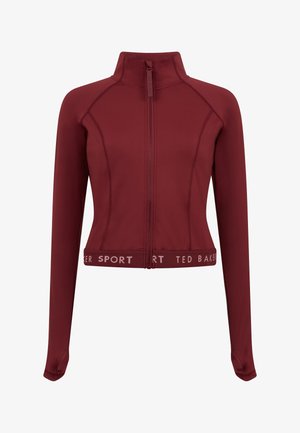 Bordo spalvos sportinė striukė su aukšta apykakle, visu užtrauktuku ir ilgomis rankovėmis. Apačioje yra kontrastingas baltas tekstinis logotipas ir tekstūruotos detalės.