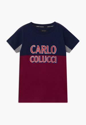 Camiseta de manga corta con la mitad superior en azul marino, la mitad inferior en burdeos, detalle gris en las mangas y texto "CARLO COLUCCI" en rojo y blanco en el frente.