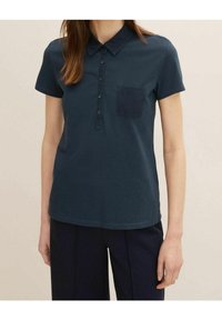 Navy blue cotton polo shirt with short sleeves, button-down collar, and a single chest pocket. Smooth texture and regular fit.