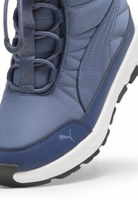 Zapatilla deportiva navy con parte superior sintética texturizada, sistema de cordones elásticos, cuello acolchado y plantilla blanca en contraste. Suela de goma.