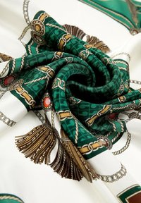 Écharpe en soie ornée d'un motif géométrique vert et blanc avec des accents dorés et des motifs décoratifs, créant une apparence texturée et luxueuse.