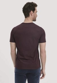 Donkerpaarse T-shirt met korte mouwen en ronde hals, gemaakt van katoen. Gladde textuur, aansluitend ontwerp, zichtbare stiksels aan de zoom en de mouwen.
