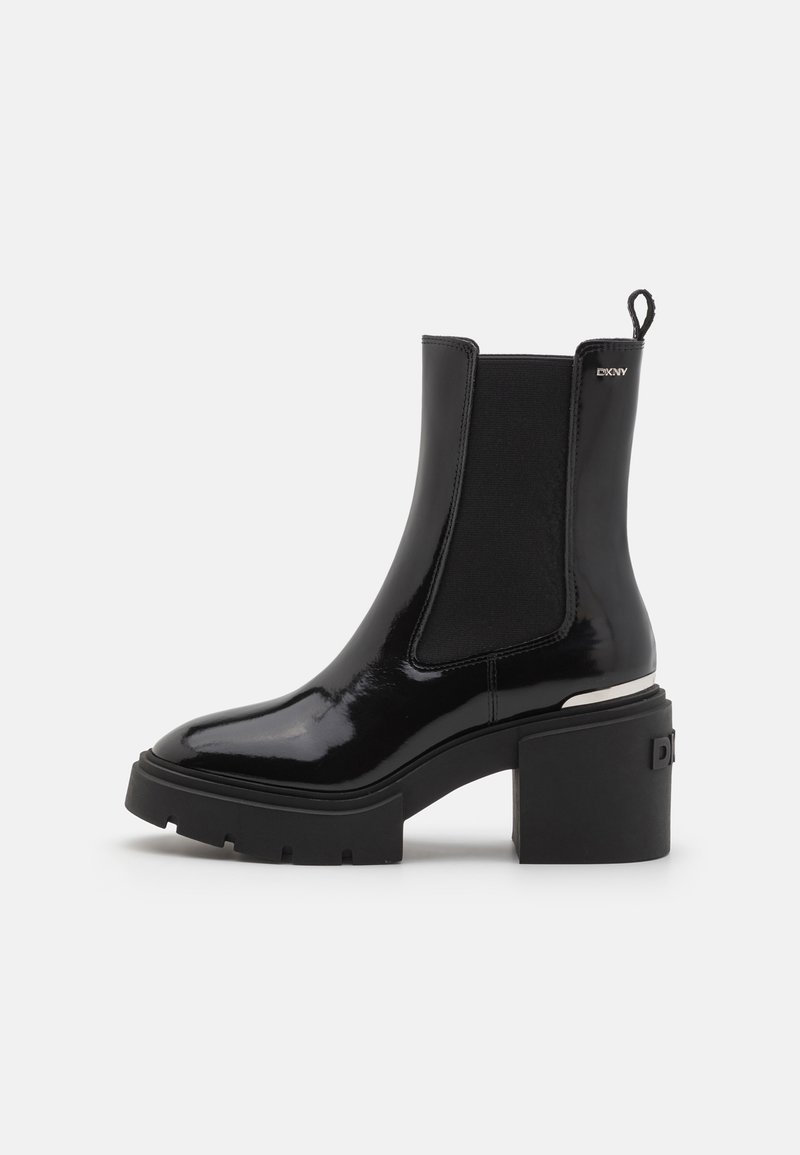 Bottine en cuir verni noir à talon bloc épais, avec panneau latéral élastique, languette, et logo DKNY argenté sur le côté supérieur.