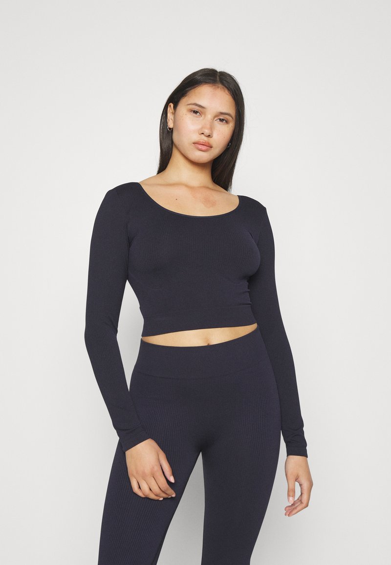 Marinblå ribbad långärmad cropped topp med bred scoop-veck, tillsammans med matchande högmidjade leggings med en slät yta.