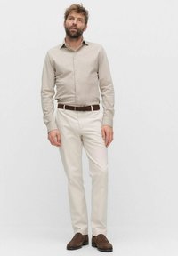 Beige overhemd met lange mouwen, lichtgekleurde broek, bruine leren riem en donkerbruine schoenen. Casual fit met een button-down kraag en gestructureerde stof.