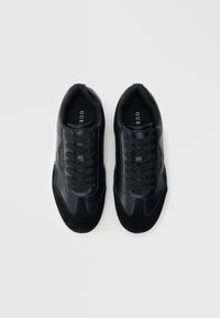 Ténis pretos feitos de couro e camurça, com colarinho acolchoado, design com atacadores, painéis laterais texturizados e sola de borracha.