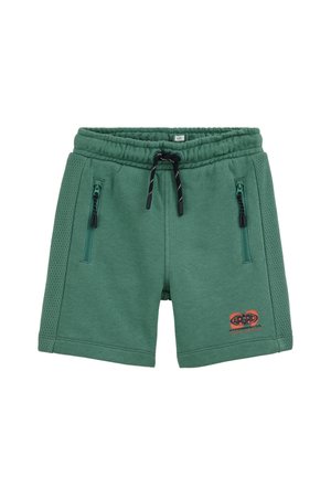 Pantaloncini verdi con coulisse, pannelli laterali in rete, due tasche frontali con zip e un piccolo logo rosso e nero sulla gamba sinistra.