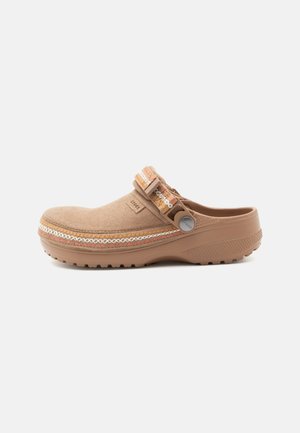 Svetlohnedý slip-on drevák s látkovým remienkom s vzorom, textúrovanou podrážkou a polstrovanou pätou, navrhnutý pre bežné pohodlie a jednoduché nosenie.