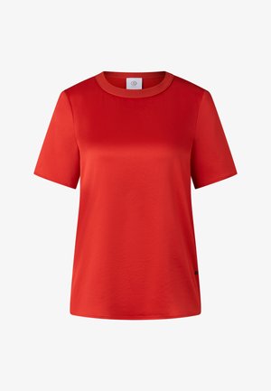 T-shirt rouge à manches courtes avec un col rond, fabriqué en tissu lisse, présentant une légère brillance et un petit logo en bas à gauche.