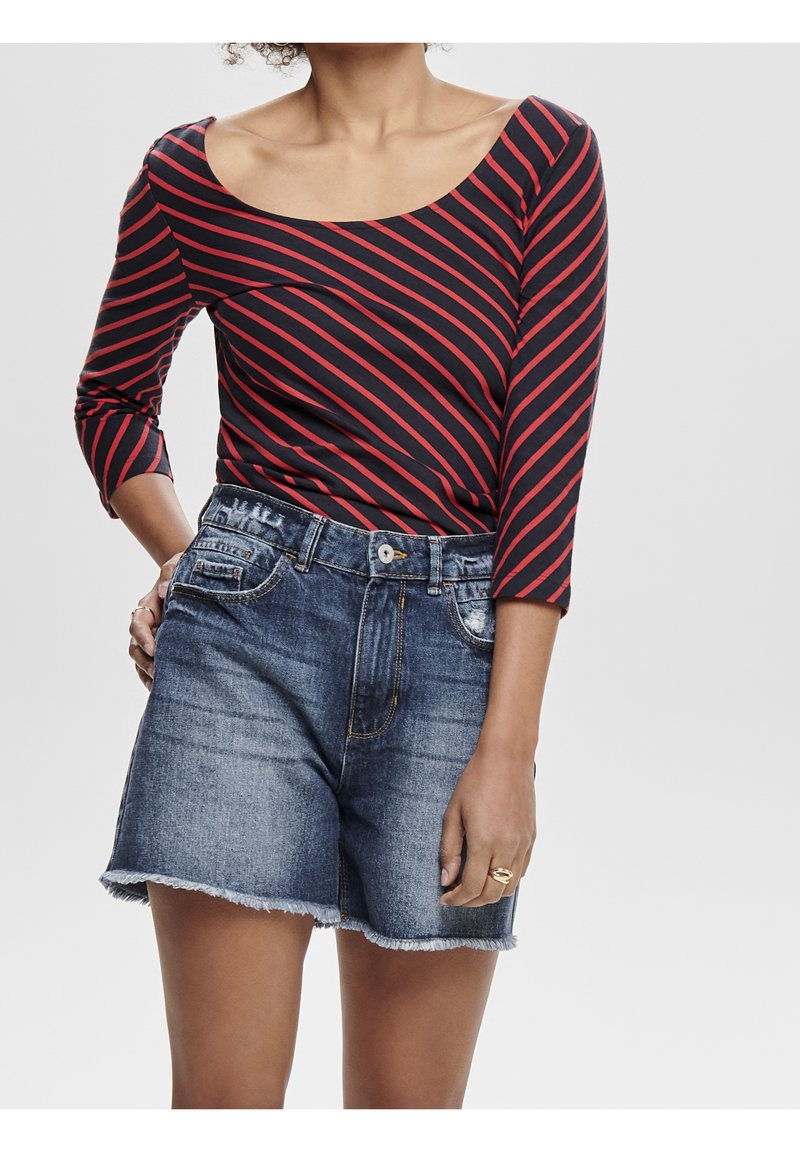 Gestreiftes Langarmoberteil in Rot und Marineblau mit rundem Ausschnitt, kombiniert mit blauen Denim-Shorts mit fransigem Saum und seitlichen Taschen.