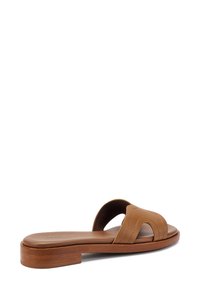 Sandal in pelle marrone con due cinturini curvi, suola in legno piatta e dettagli di cucitura sottili per texture e struttura.
