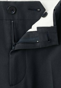 Pantaloni bleumarin cu fermoar și nasture la închidere, având o căptușeală interioară contrastantă și un material neted, texturat.