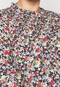 Lyhythihainen kukkakuosiselkäpaita, jossa musta tausta ja monivärisiä kukkia. Rypytetty kaula-aukko ja pehmeä kangas, jossa on hieno tekstuuri.