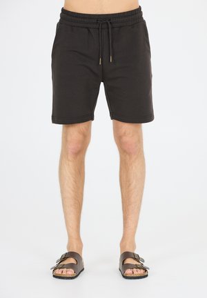 Sorte sweatshorts med elastisk talje, snøre og opfoldede kanter. Båret med brune sandaler med to justerbare remme.