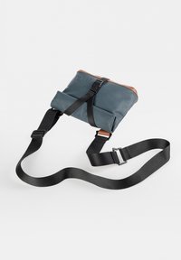 Blaue wasserdichte Tasche mit braunem Lederakzent, verfügt über ein Umschlagdesign und einen verstellbaren schwarzen Riemen. Mit sicherer Schnallenverschluss.