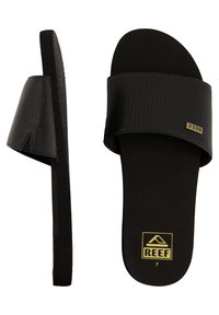 Zwarte slide-sandalen met een gestructureerd krokodillenpatroon op de band, een zachte zwarte voetbed en een gouden "REEF" logo aan de zijkant.