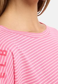 Rosa och vit randig t-shirt med rund halsringning och korta ärmar. Tyget verkar mjukt med en lätt stretch.