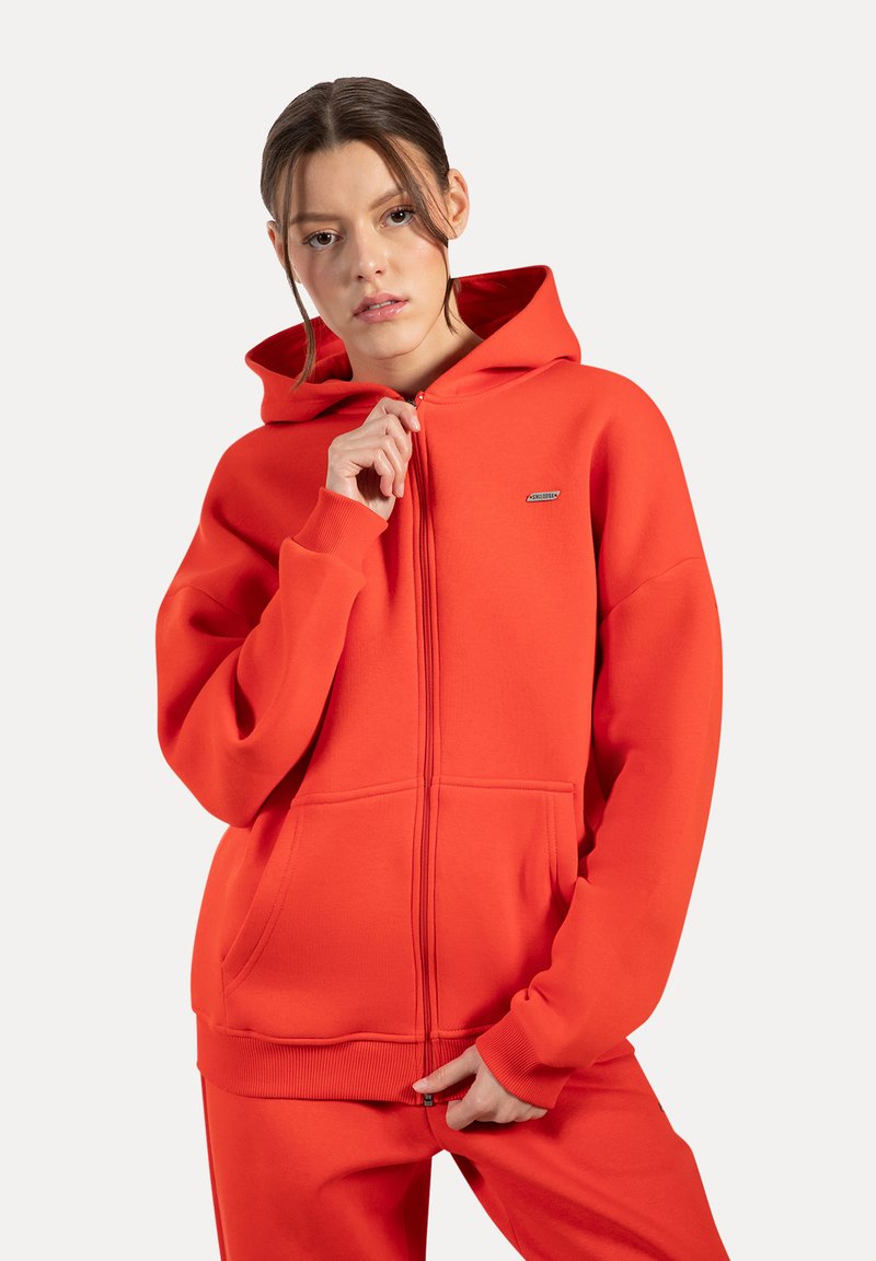 Rode hoodie met rits gemaakt van zacht materiaal, met een trekkoordcapuchon, ribgebreide manchetten en voorzakken. Kleine logodetail op de borst.