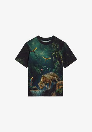 Póló dzsungeles mintával, amelyen egy víznél ivó leopárd és színes papagájok láthatók, ahogy a sűrű zöld levelek között repülnek és ülnek.