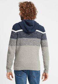 Felpa con cappuccio lavorata a maglia in blu scuro, grigio e strisce bianche. Caratterizzata da una finitura texturizzata, polsini a coste e una tasca a marsupio.