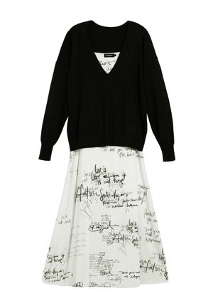 Fekete kötött pulóver V-nyakkivágással, fehér ruhával párosítva, amely kézzel írt fekete szöveget és absztrakt mintákat tartalmaz. A pulóver hosszú ujjú.