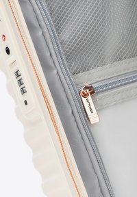 Walizka z twardą skorupą w kolorze kremowym z szarymi zamykanymi na zamek przegródkami. Posiada zamek szyfrowy oraz różowo-złote suwaki z grawerem "WITTCHEN".