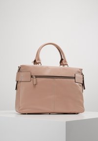 Rosa läderhandväska med dubbla handtag, en framficka med dragkedja och en slät yta. Har minimala metallaccenter och en strukturerad design.