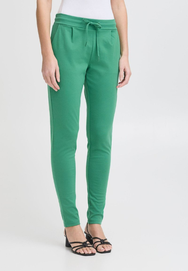 Groene, rekbare joggers met een elastische tailleband, slim fit en zijzakken. Gepaard met zwarte sandaaltjes met bandjes.