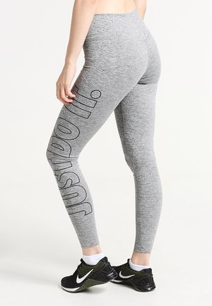 Leggings de sport gris avec une taille haute, texture lisse et impression verticale "just do it" en noir le long de la jambe gauche.
