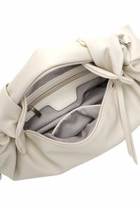 Kremowa skórzana torebka z węzłowym wzorem. Wnętrze zawiera kieszeń na zamek i miękką szaro-białą podszewkę, oferującą wszechstronne opcje przechowywania.