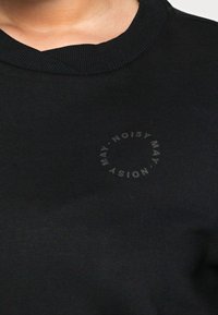 Zwarte sweatshirt met een geribde ronde hals en een circulair logo dat in een subtiele textuur op de voorkant is gedrukt. Soepele stof, minimalistisch ontwerp.