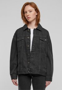 Zwarte denimjas met een kraaghalslijn, sluiting met knopen aan de voorkant, twee borstzakken en verlaagde schouders voor een ontspannen pasvorm.