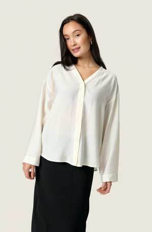 White long-sleeve button-up shirt with a V-neck, soft textured fabric, and a relaxed fit, paired with a black pencil skirt.